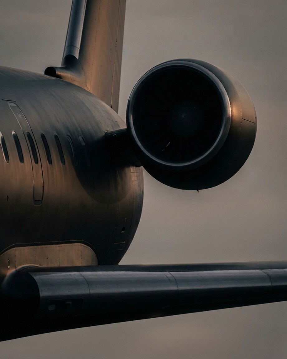 Close editorial detail of a matte black private jet's tail, engine and wing at dusk